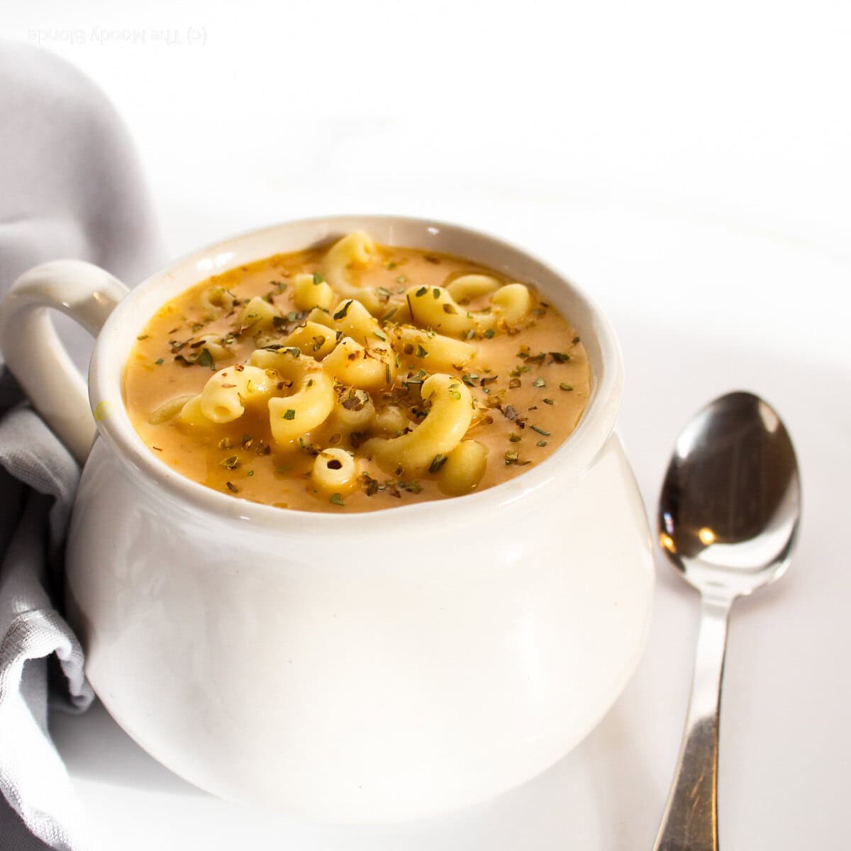 cheeseburger soup in a white bowl with a silver spoon on the right