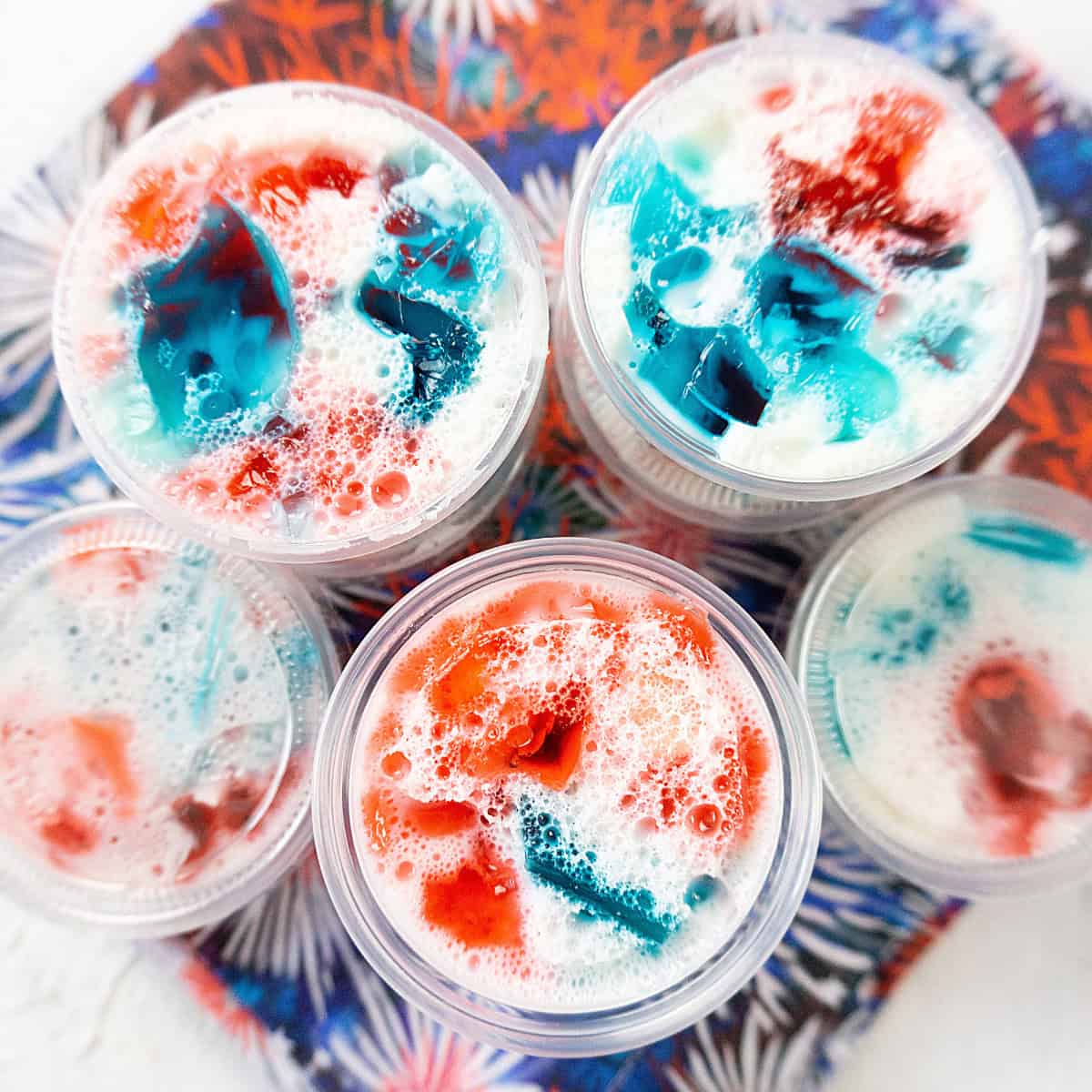 Red, white, and blue jello shots sitting on a patriotic napkin ready for a 4th of July barbecue