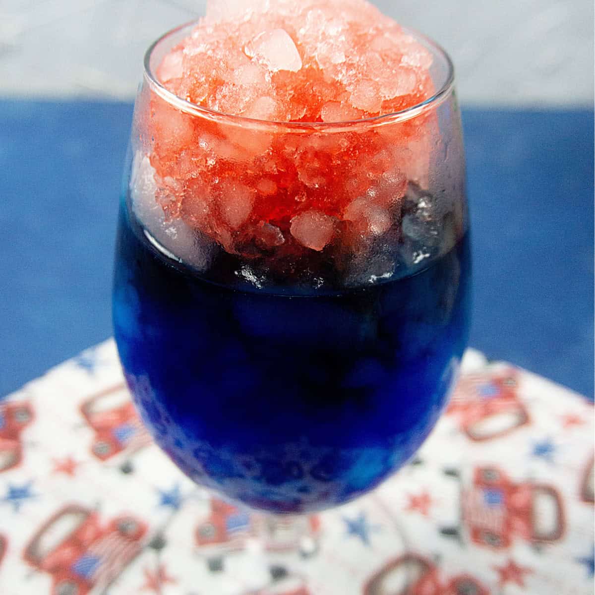 Red, white, and blue slushie in a wine glass on a blue background