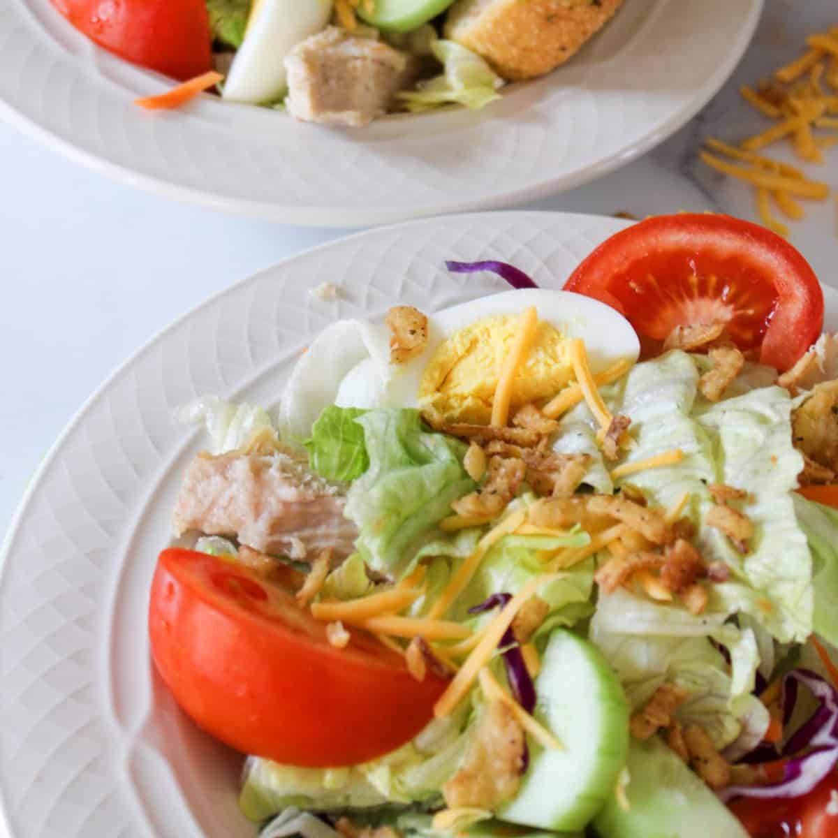 Copycat Zaxby's Cobb Salad in a white bowl with another salad in the background