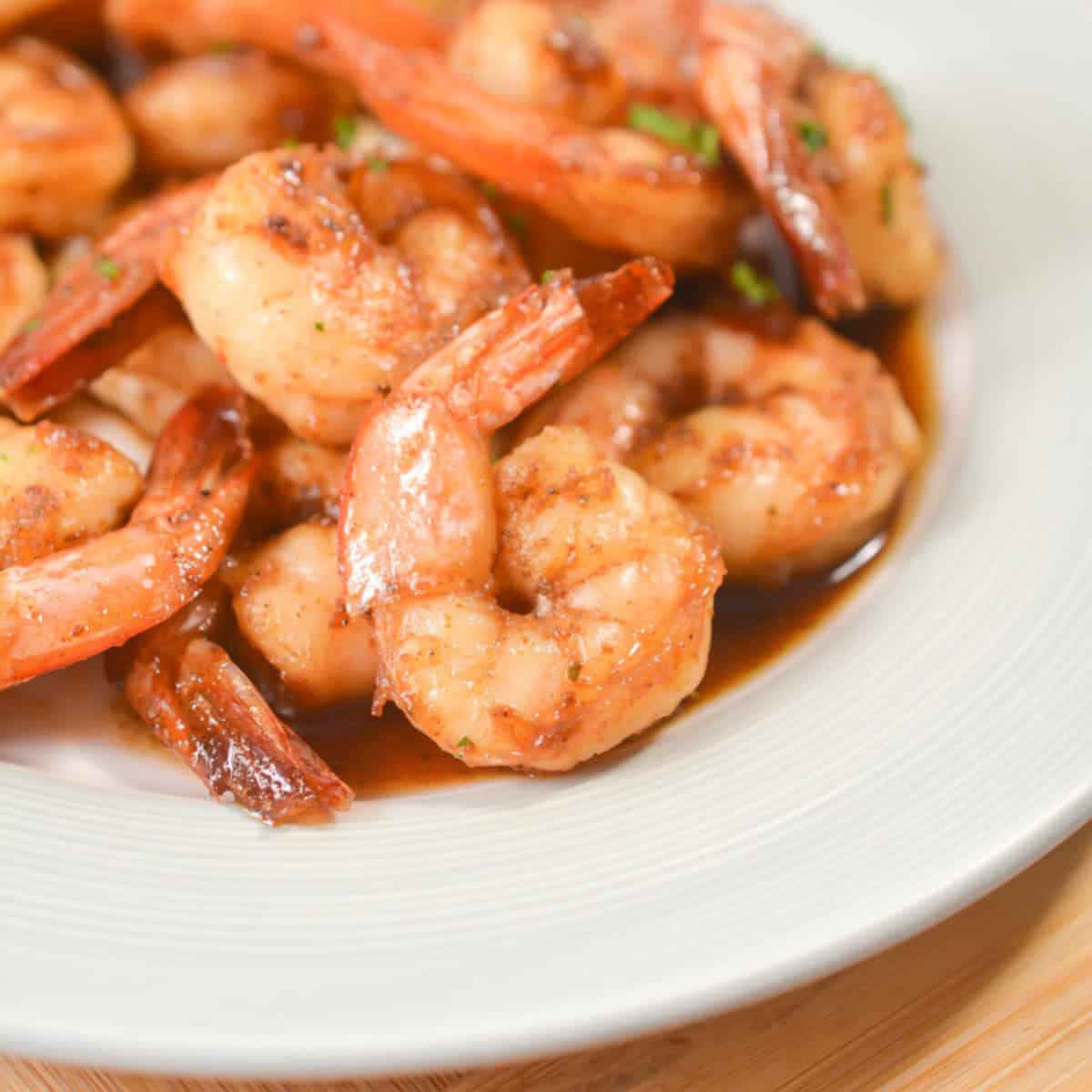 Cooked shrimp in a white bowl seasoned with sweet honey and Old Bay seasoning.