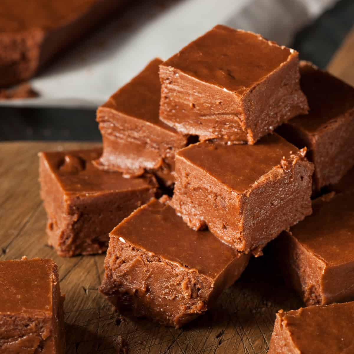 a stack of Instant Pot Fudge squares made with condensed milk on a wooden cutting board.