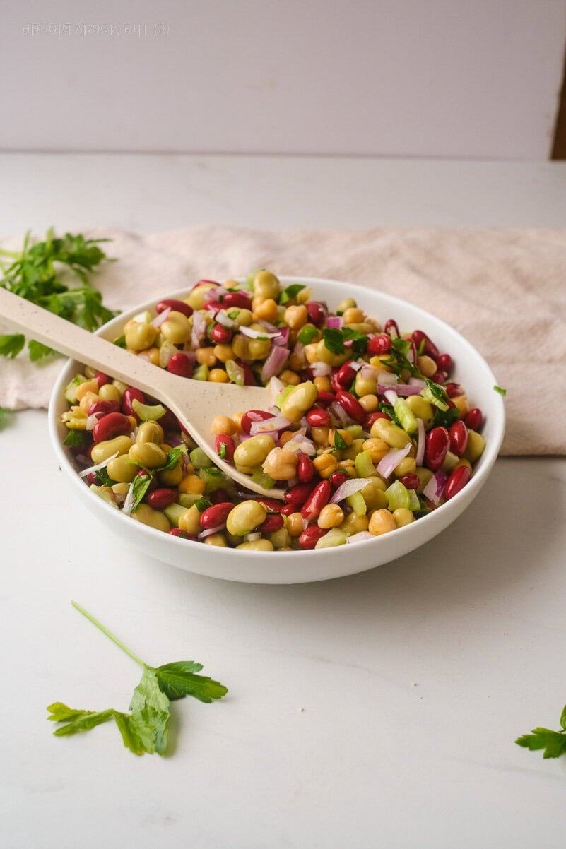 3 Bean Salad by The Moody Blonde in a white bowl on a light background with a white spoon