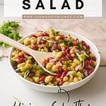 3 Bean Salad With Italian Dressing Title Graphic for Pinterest featuring a white bowl with salad and a wooden spoon on a beige background